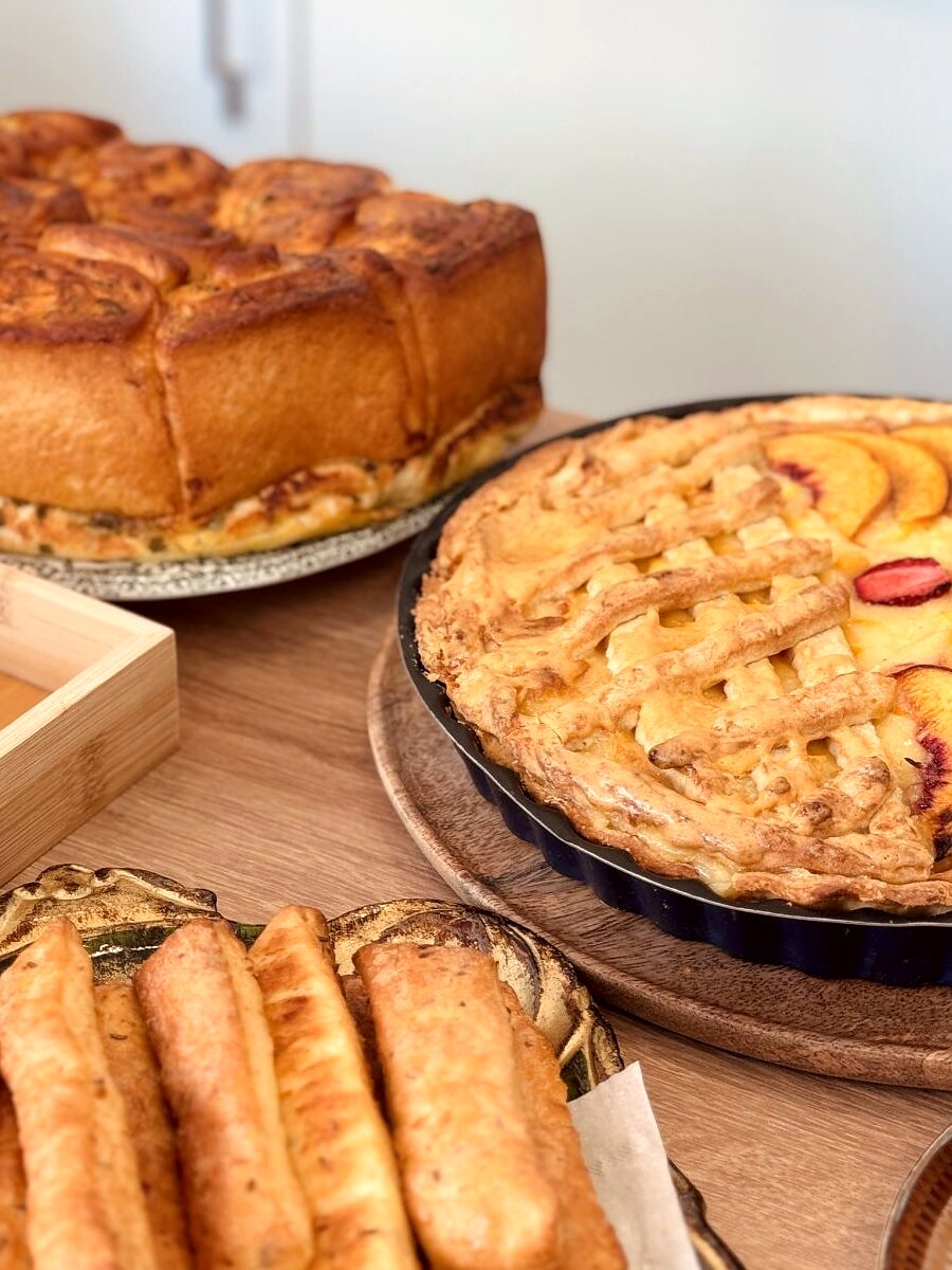 Tăvi de lemn cu plăcintă cu mere, chec și foietaje, scoase din cuptor